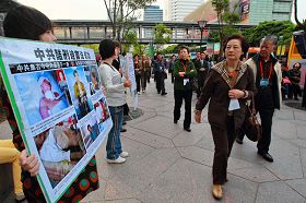 '大陆游客在台北信义广场前一零一大楼前观看法轮功学员举的真相看板'