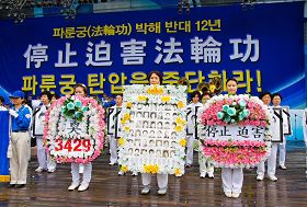 '二零一一年七月十六日，韩国八大市民团体与法轮功学员冒雨在首尔广场举行联合集会，谴责中共对法轮功长达十二年的人权迫害。图为现场展示被中共迫害致死的中国法轮功学员。'