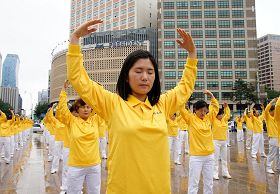 '二零一一年七月十六日，韩国八大市民团体与法轮功学员冒雨在首尔广场举行联合集会，谴责中共对法轮功长达十二年的人权迫害。图为韩国法轮功学员集体炼功场面。'